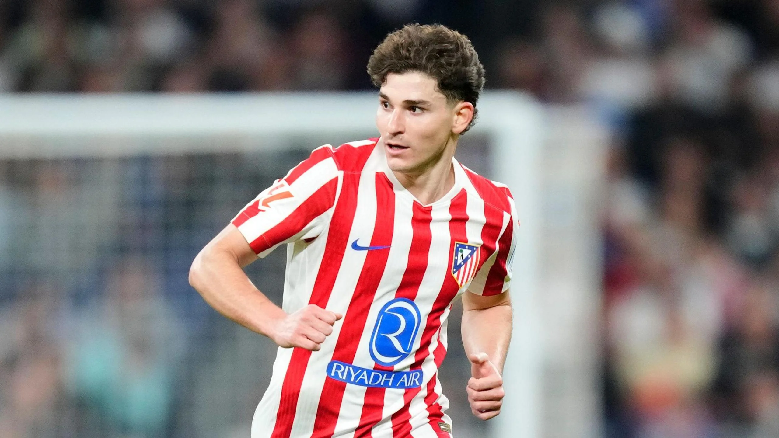 Julian Alvarez running in Atletico Madrid's red and white striped home shirt
