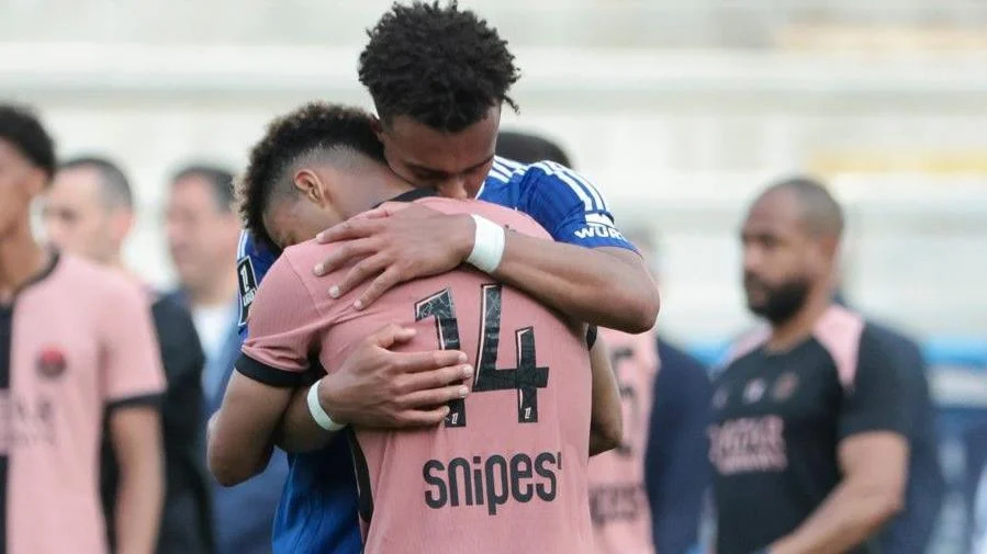 Guela Doue of Strasbourg (blue jersey) hugs his brother Desire Doue of Paris St-Germain following a match in May 2025