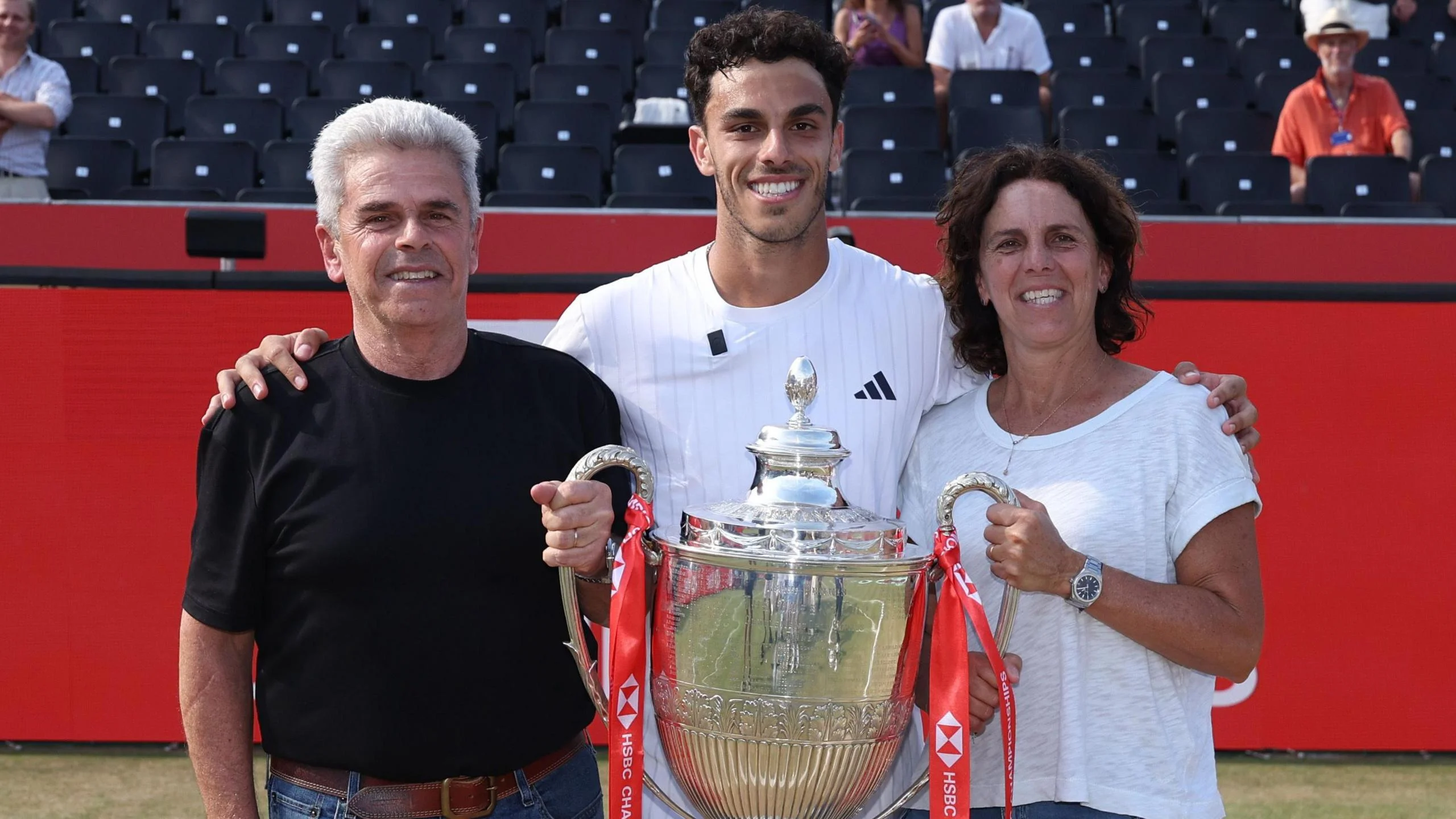 Francisco Cerundolo poses with the Queen's trophy alongside his parents