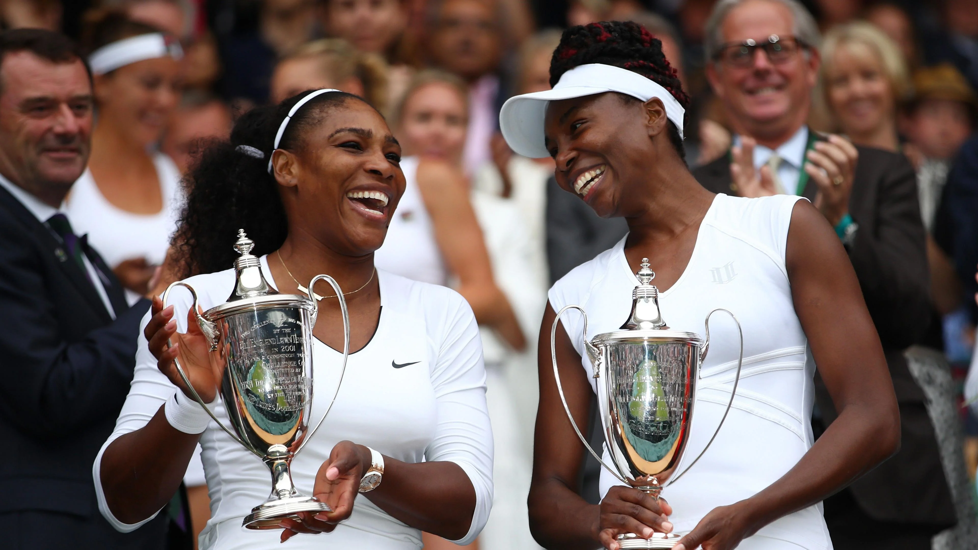 Serena and Venus Williams pose with the women's doubles trophies at Wimbledon in 2016