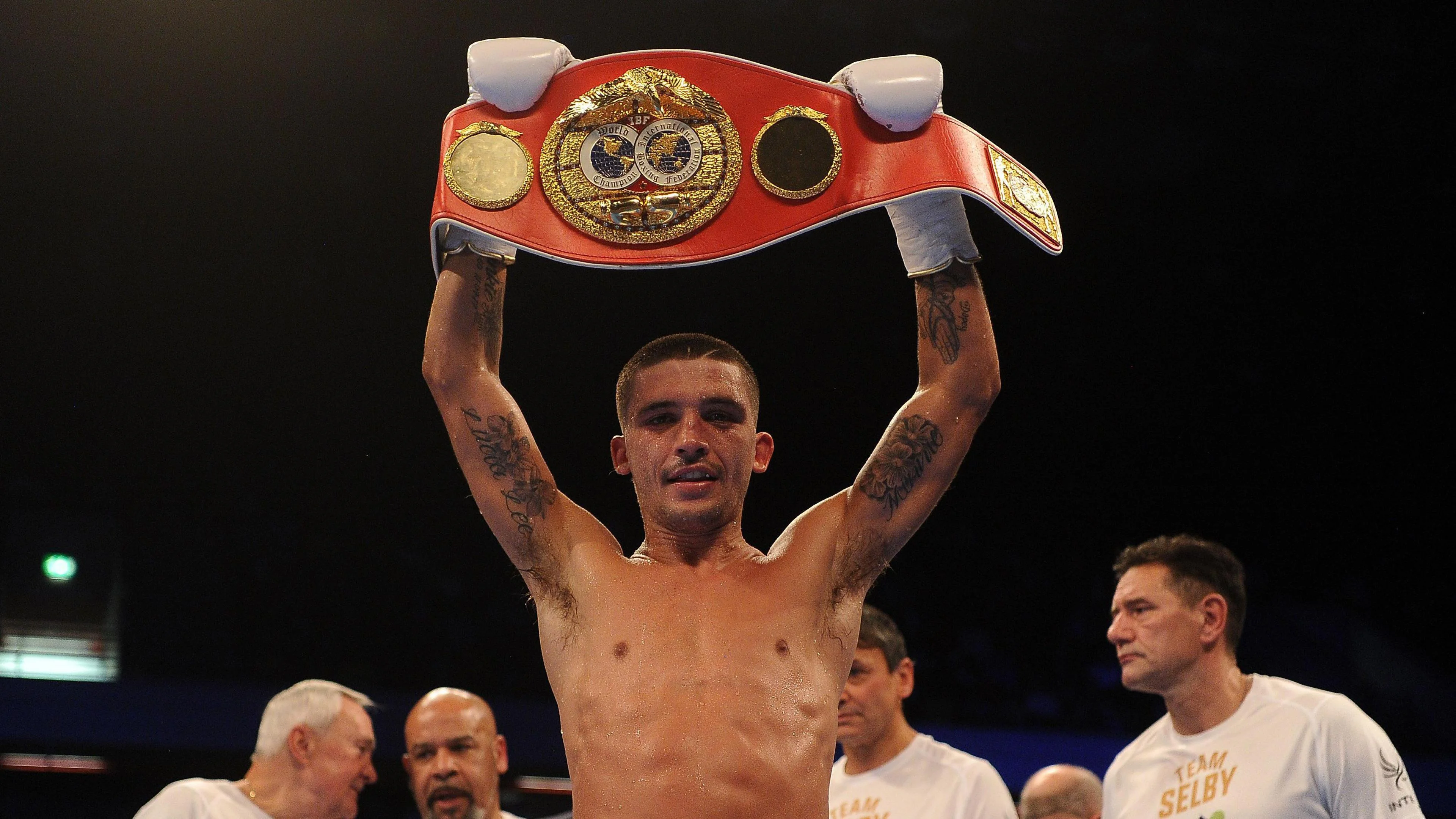 Selby holds aloft a red world title belt after a fight